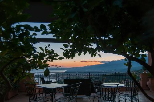 a patio with tables and chairs and a sunset at Villa Le Terrazze Charming Rooms in Taormina