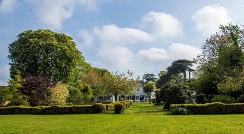 a house in a field with trees and bushes at Cedar House Boutique B&B in Burton