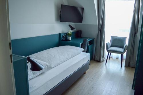 a bedroom with a bed and a tv and a chair at Pension Elisabeth - Rooms & Apartments in Salzburg