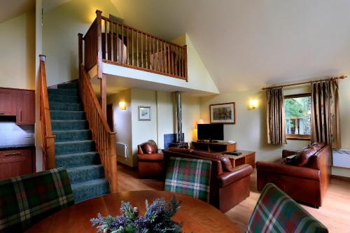 a living room with a staircase and a table and chairs at Macdonald Woodland Lodges at Macdonald Aviemore Resort in Aviemore
