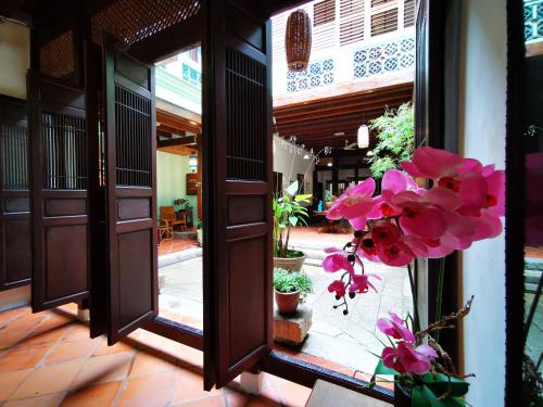 an open door to a courtyard with pink flowers at East Indies Mansion in George Town