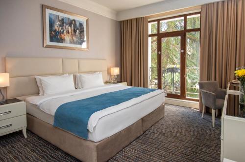 a bedroom with a large bed and a large window at City Avenue Hotel in Tbilisi City