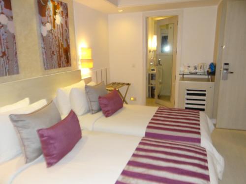 a bedroom with a white bed with red and purple pillows at The Ashtan Sarovar Portico in New Delhi