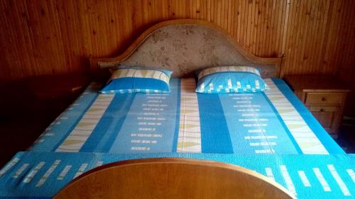 a blue bed with a wooden headboard and two pillows at pensiunea Gabriela in Durau