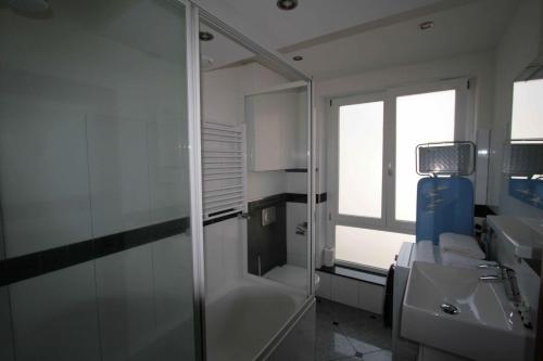uma casa de banho com uma cabina de duche em vidro e um lavatório. em Amosa Liège City Centre Apart Regence 10 em Liège