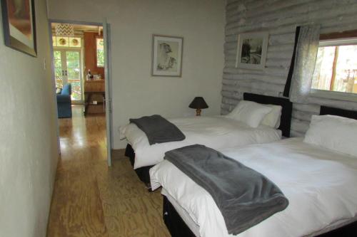1 dormitorio con 2 camas y pared de piedra en Old Pine Cabin Karkloof, en Yarrow