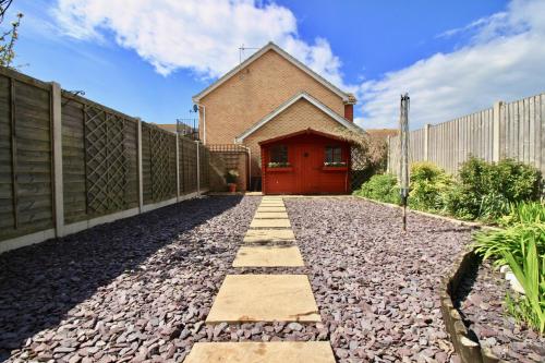 a house with a red door and a fence at Seascape in Clacton-on-Sea