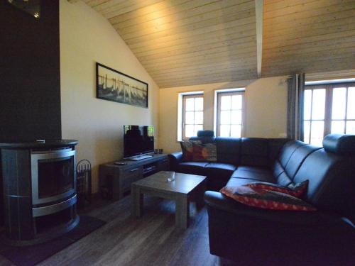 a living room with a couch and a tv at Spacious Chalet in Vielsalm with Garden in Vielsalm