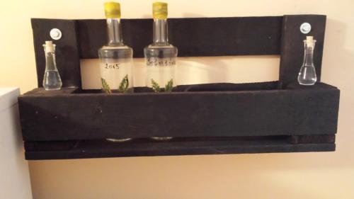 a black shelf with three wine bottles on it at Guest House Šebeš in Bezdan