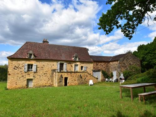 an old stone house in a field with a bench at Beautiful holiday home in wooded grounds near Villefranche du P rigord 7 km in Villefranche-du-Périgord