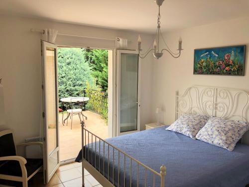 une chambre avec un lit et un balcon avec une table dans l'établissement Aux Cyprès du Sud : mer et montagne, à Logrian-et-Comiac-de-Florian