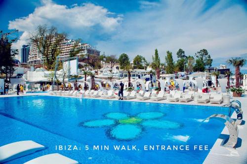 a large swimming pool with white chairs and a blue at Gagarin Plaza Apartment in Odesa
