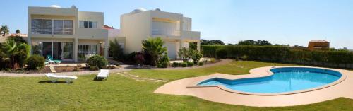 a villa with a swimming pool in front of a house at Villas Oceano in Albufeira