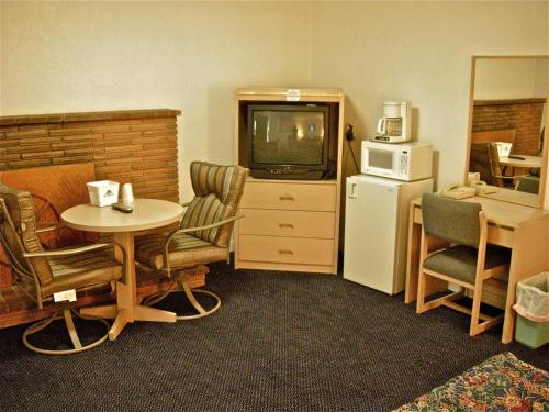 Habitación de hotel con TV, mesa y sillas en Hub Motel, en Redmond