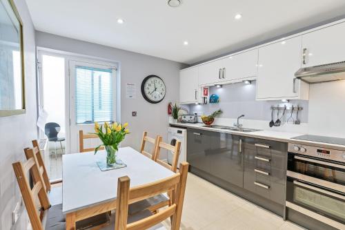 a kitchen with a table and chairs and a clock on the wall at Park View House - By My Getaways in Brighton & Hove