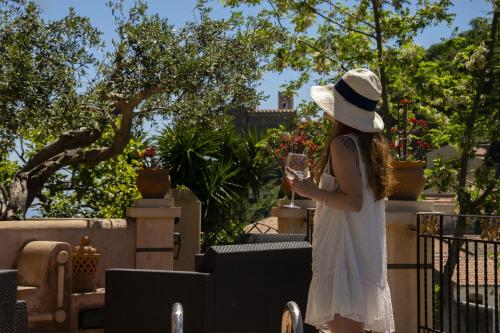 a woman in a white dress and hat holding a glass at Villa Laura in Savoca 