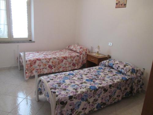 a room with two beds and a table with a bedskirts at Santu Luisu in Galtellì
