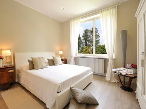 Un dormitorio con una gran cama blanca y una ventana en Villa La Maggiorana, en Rivoli