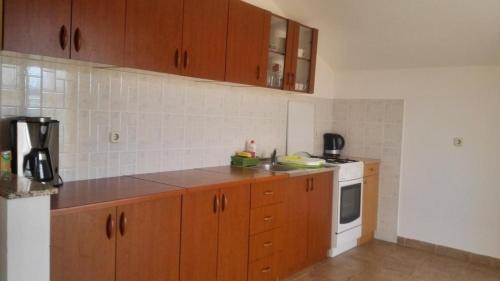 uma cozinha com armários de madeira e um fogão branco em Apartment Tina -with terrace and sea view em Obrovac