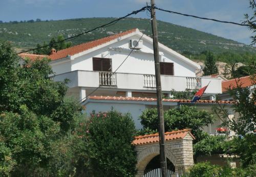 uma casa branca com uma varanda numa colina em Apartment Tina -with terrace and sea view em Obrovac