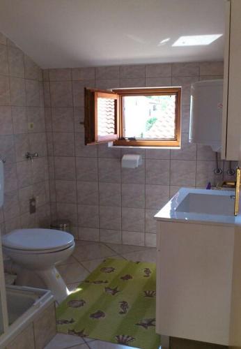 uma casa de banho com um WC, um lavatório e uma janela em Apartment Tina -with terrace and sea view em Obrovac