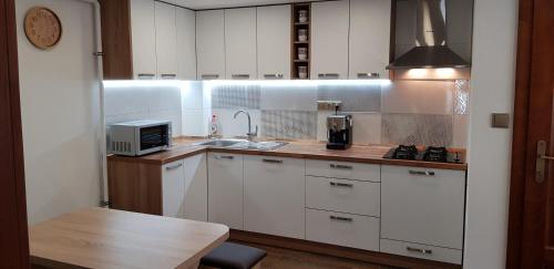 a small kitchen with white cabinets and a sink at Apartman Zatura in Vyšnie Šuňava