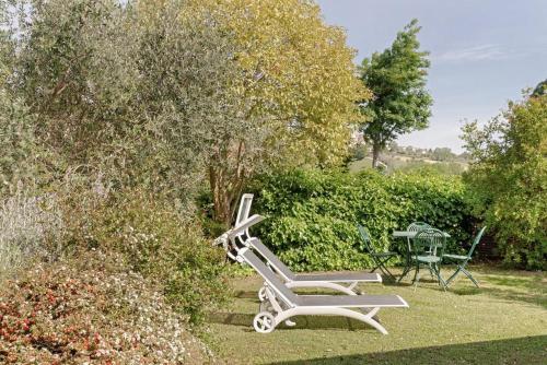 a white bench sitting in the grass in a garden at Casali Marchigiani - Ville vacanza private con piscina in Ostra