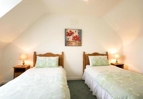 two twin beds in a room with two lamps at Ballybunion Holiday Cottages No 7 in Ballybunion