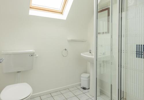 La salle de bains blanche est pourvue de toilettes et d'un lavabo. dans l'établissement Ballybunion Holiday Cottages No 7, à Ballybunion