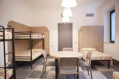 Ostello Alfieri 2 في تورينو: غرفة مع سرير بطابقين وطاولة وكراسي