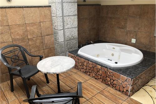 a bathroom with a tub and a chair and a table at ホテルメイフェア Adult Only 男塾ホテルグループ in Yōkaichi