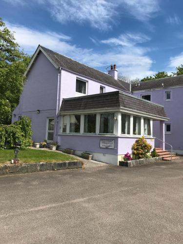 a white house with a porch on a street at Glenlochy Nevis Bridge Apartments in Fort William