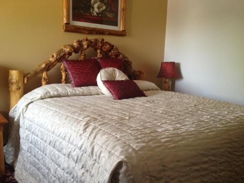 a bedroom with a large bed with red pillows at Buffalo Bill's Antlers Inn in Cody