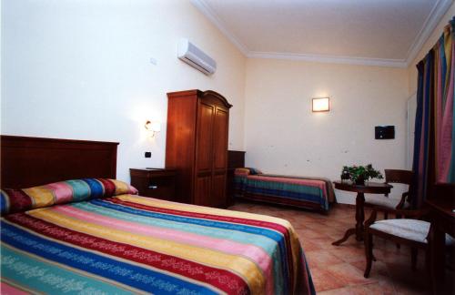 una habitación de hotel con una cama con una manta colorida en B&B Villa Rosa, en San Leone