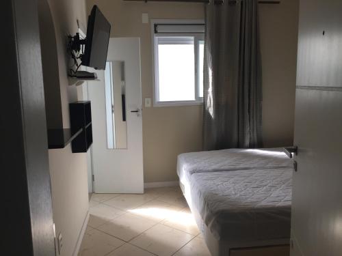 ein kleines Schlafzimmer mit einem Bett und einem Fenster in der Unterkunft Apartamento Estúdio Vista Mar in Balneário Camboriú
