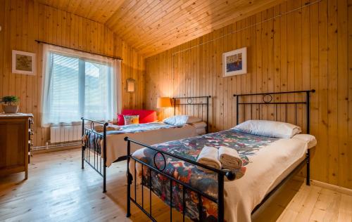 two beds in a room with wooden walls at Rivendell in Borjomi