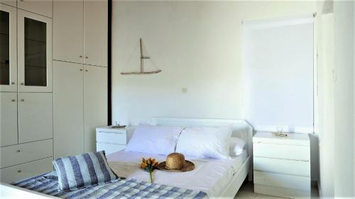 a white bedroom with a bed with a hat on it at Stella's Home in Koronos in Kóronos