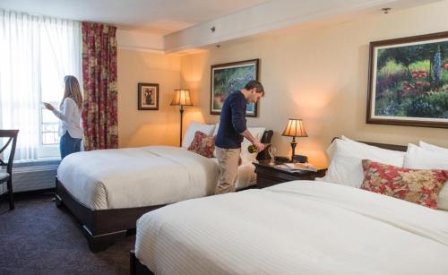 a man standing in a bedroom next to a bed at Le St-Martin Bromont Hotel & Suites in Bromont