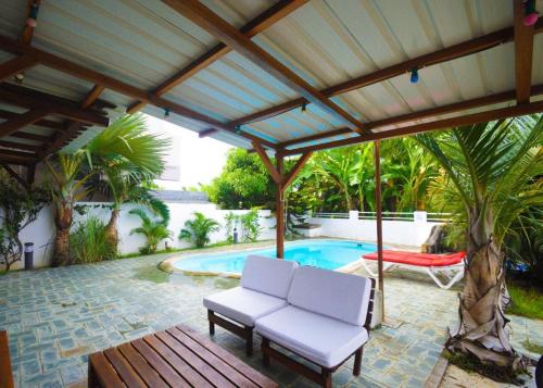 un patio con 2 sillas blancas y una piscina en Pereybere Villa Valari with Pool Near Beach en Pereybere