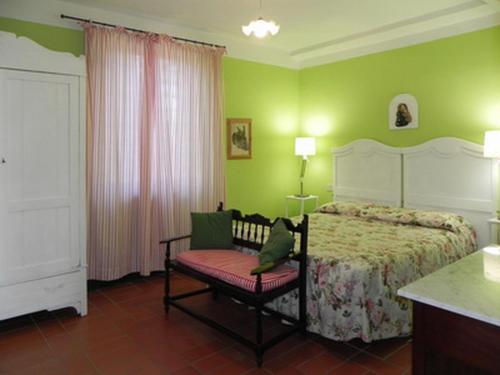 a bedroom with a bed and a chair and green walls at Vignagrande Agriturismo in Saturnia