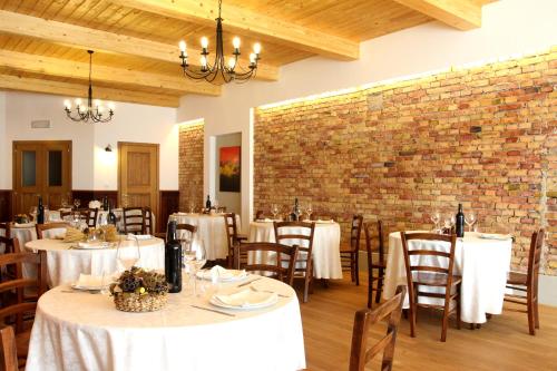restauracja z białymi stołami i krzesłami oraz ceglaną ścianą w obiekcie Agriturismo Le Giarine w mieście Fogliano Redipúglia