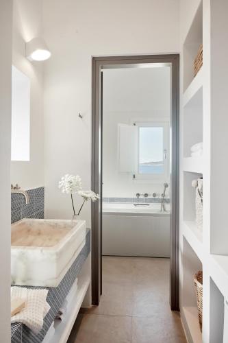 a white bathroom with a tub and a sink at Milos Breeze Boutique Hotel in Pollonia