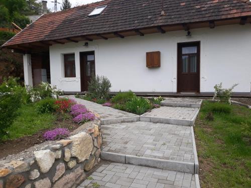 a white house with a stone wall in front of it at Zempléni Pitvaros Pihenő in Telkibánya
