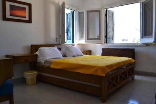 a bedroom with a bed with yellow sheets and two windows at La Stanza Chalet in Dawwār ‘Abd al ‘Aţī Abū ‘Ajūz