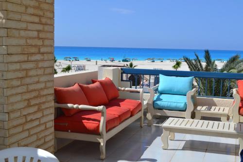 a patio with a couch and chairs and the beach at La Stanza Chalet in Dawwār ‘Abd al ‘Aţī Abū ‘Ajūz