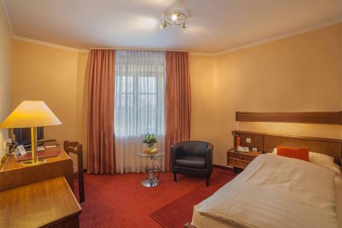 a hotel room with a bed and a desk and a chair at Hotel Pontivy in Wesseling