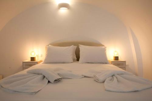 a bed with white sheets and pillows with two lamps at Centrio Fira Suites in Fira
