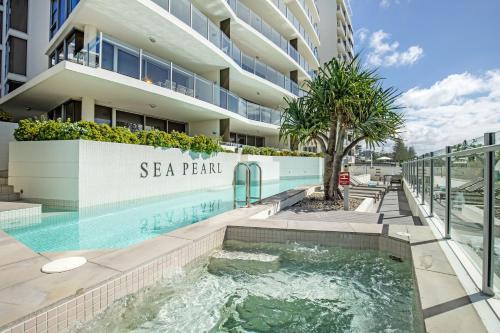 a swimming pool in front of a building at Sea Pearl A1 Beach Resort in Mooloolaba