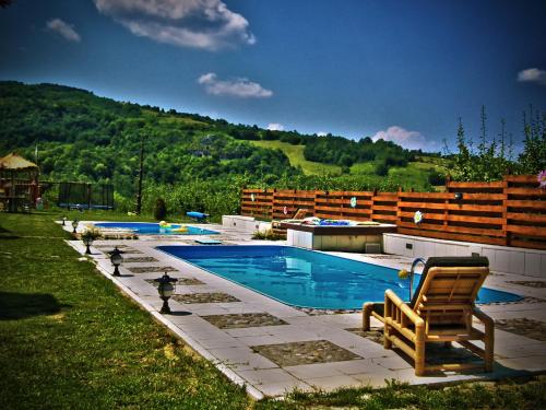 - une piscine avec un fauteuil à bascule et une chaise dans l'établissement Zdravkovac Country Club, à Jarmenovci