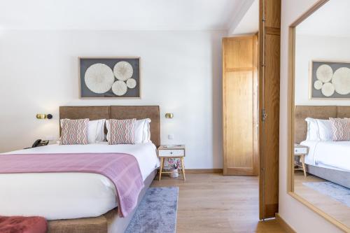 een slaapkamer met 2 bedden en een spiegel bij With You Suites in Lissabon